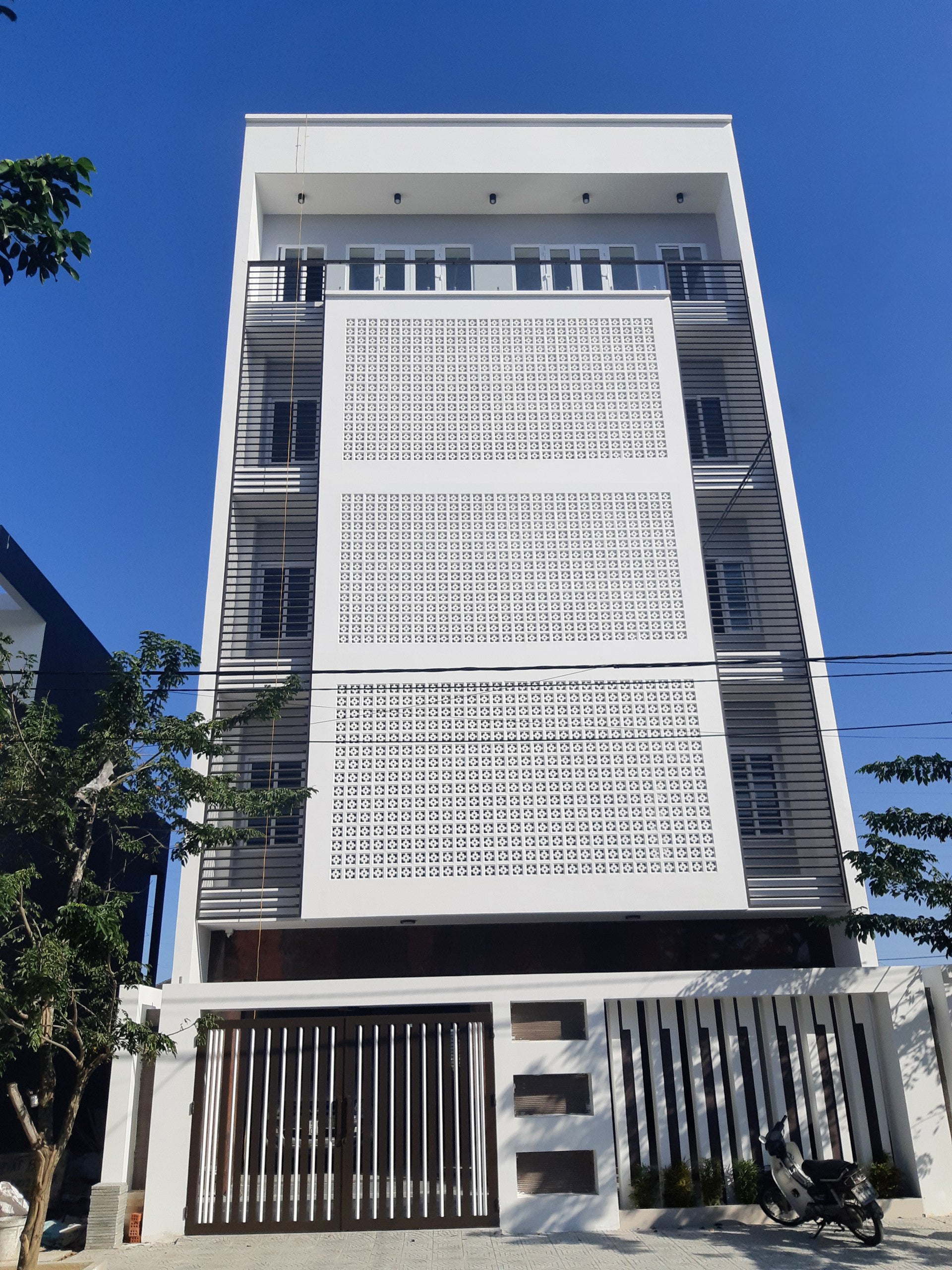 Tong by New York Cement Tile: a modern white building with stylish partitions and balconies under a clear blue sky.