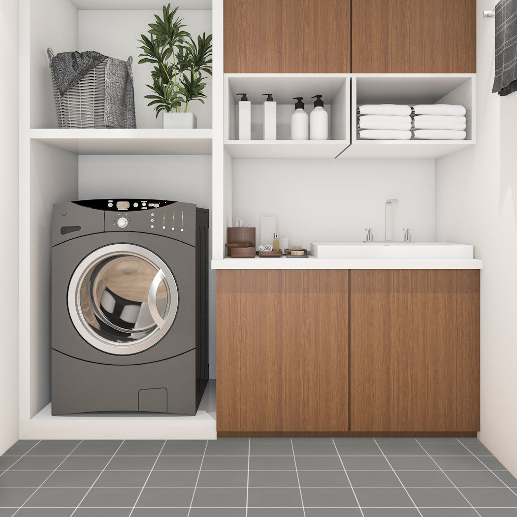 Modern laundry room featuring New York Cement Tile 2202-Solid sample on the floor, with washer, sink, plants, and wood cabinets.