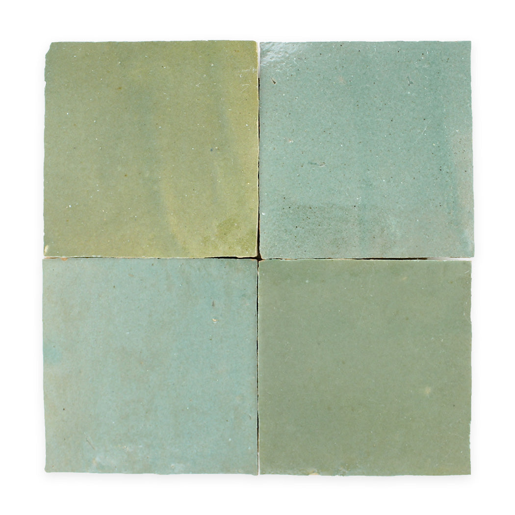 Four square ceramic tiles in muted green and blue shades arranged in a 2x2 grid on a white background.