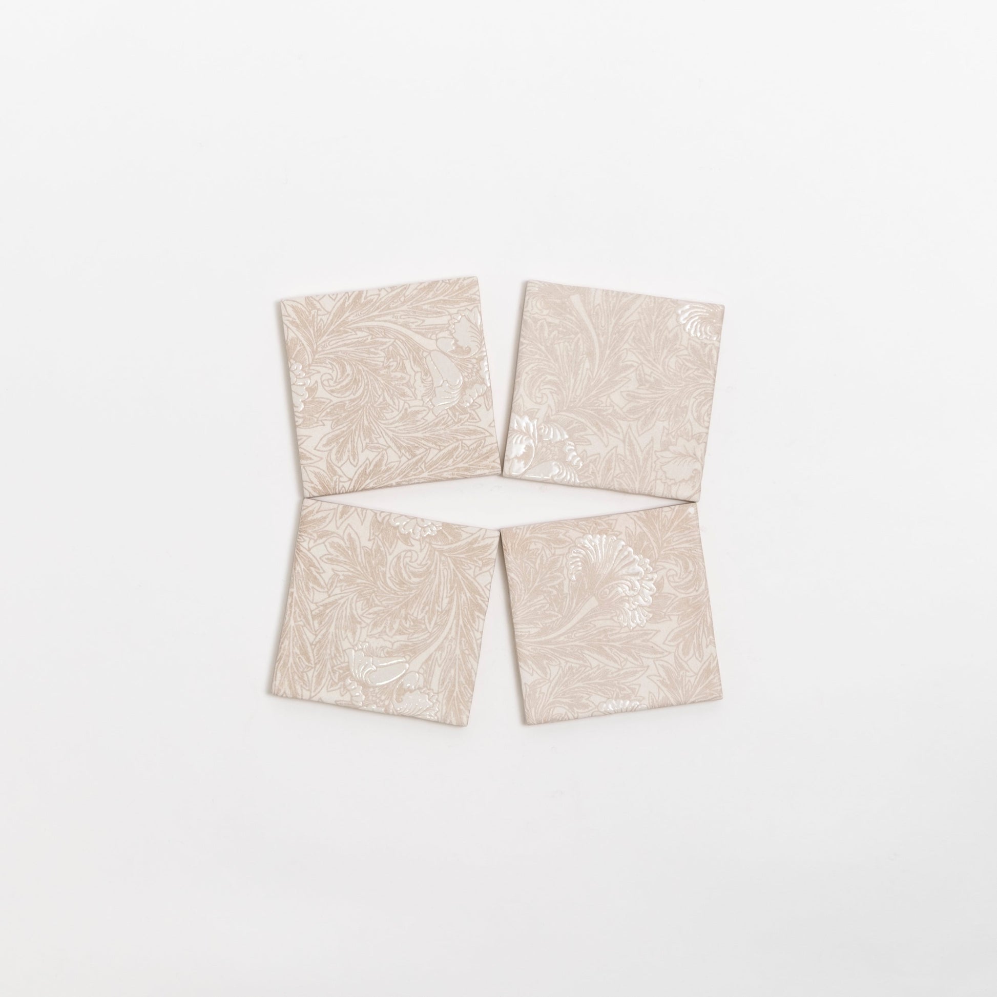 Four Grace Deco tiles by Cottage Ivy, beige with a subtle floral pattern, are arranged in a diamond shape on white.