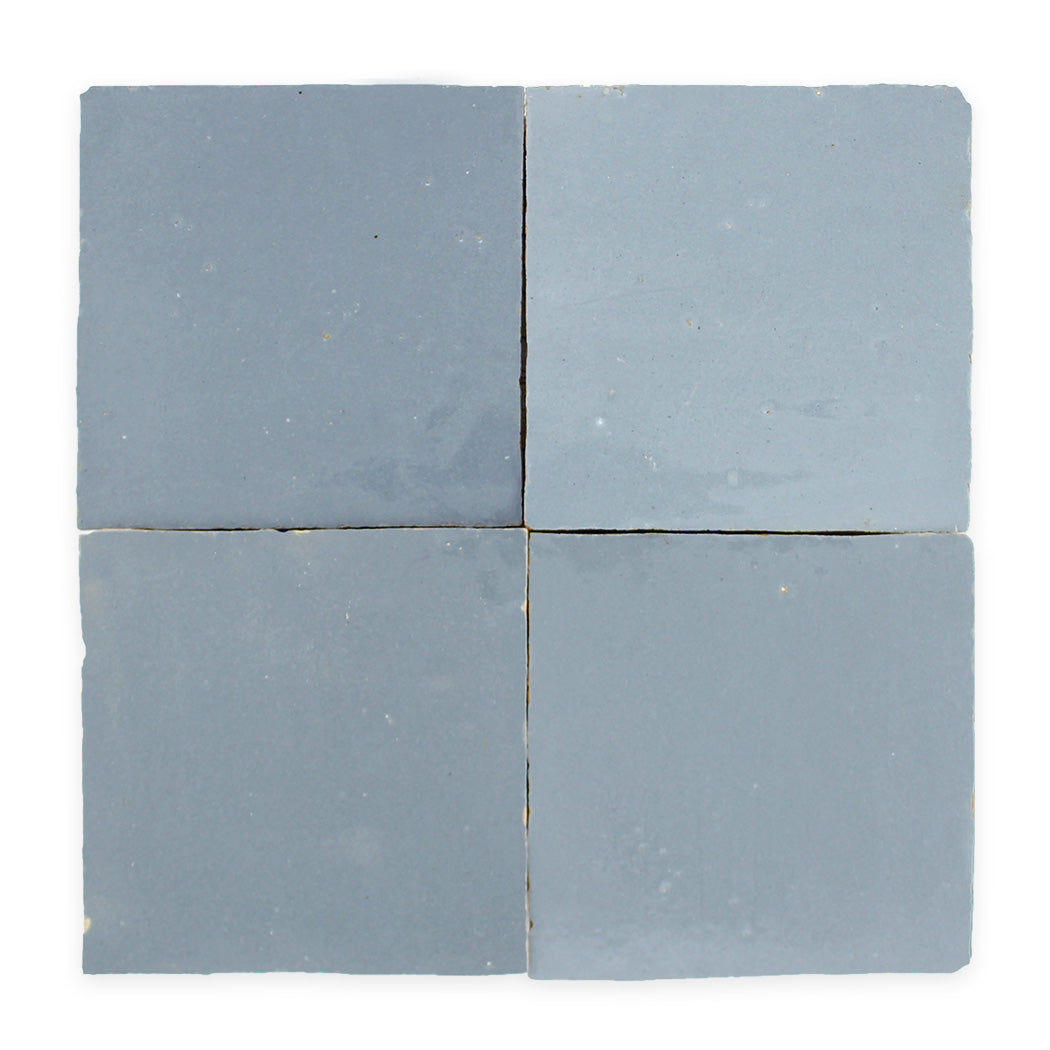 Four square, matte blue-grey tiles arranged in a grid with slight gaps between each tile on a white background.