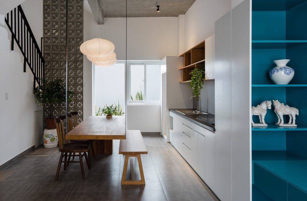 Modern kitchen with wooden table, bench, plants, blue shelves, and Beeza Sample breeze blocks by New York Cement Tile.