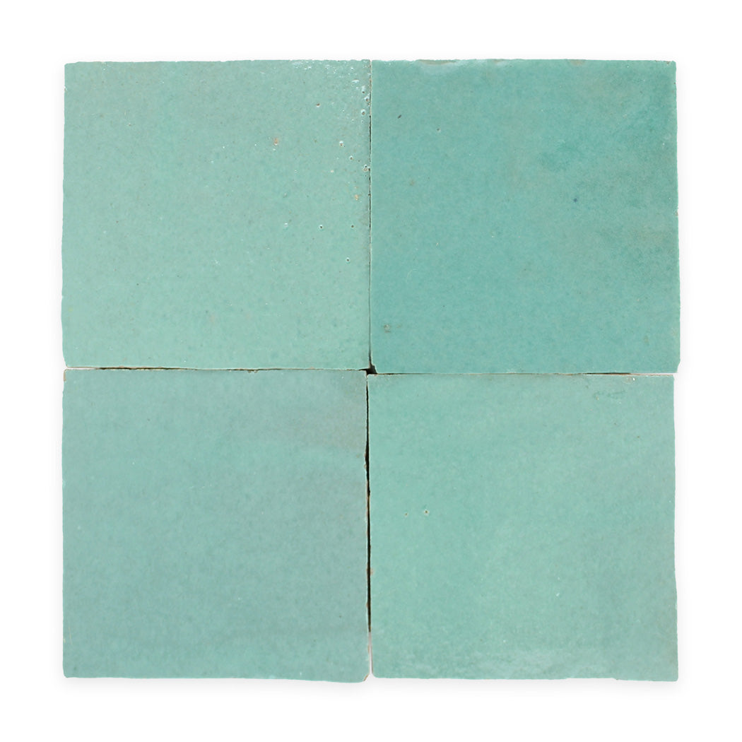 Four square, light teal ceramic tiles arranged in a 2x2 grid on a white background.
