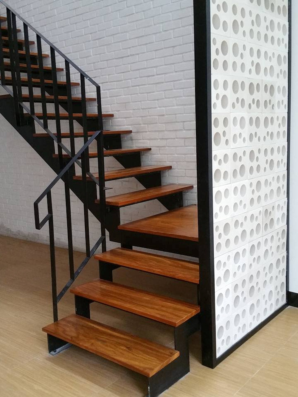 Jami by New York Cement Tile: Modern wooden staircase with black railing beside a wall featuring Jami breeze blocks.