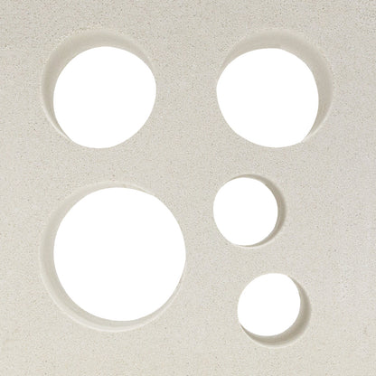 Five circular holes of varying sizes in Jamaica - NBB-015 by New York Cement Tile are arranged on an off-white surface.
