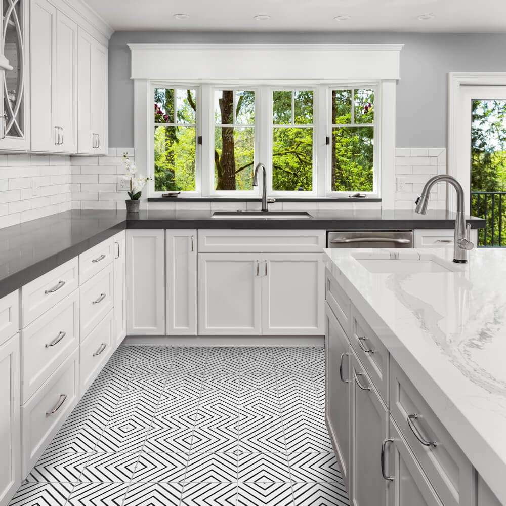 Modern white kitchen with New York Cement Tile N20-437 B&W, large windows, gray counters, and stainless steel fixtures.