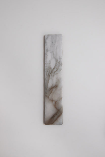 A Tosca Macchia Vecchia marble sample with gray and brown veining stands vertically on a plain white background.