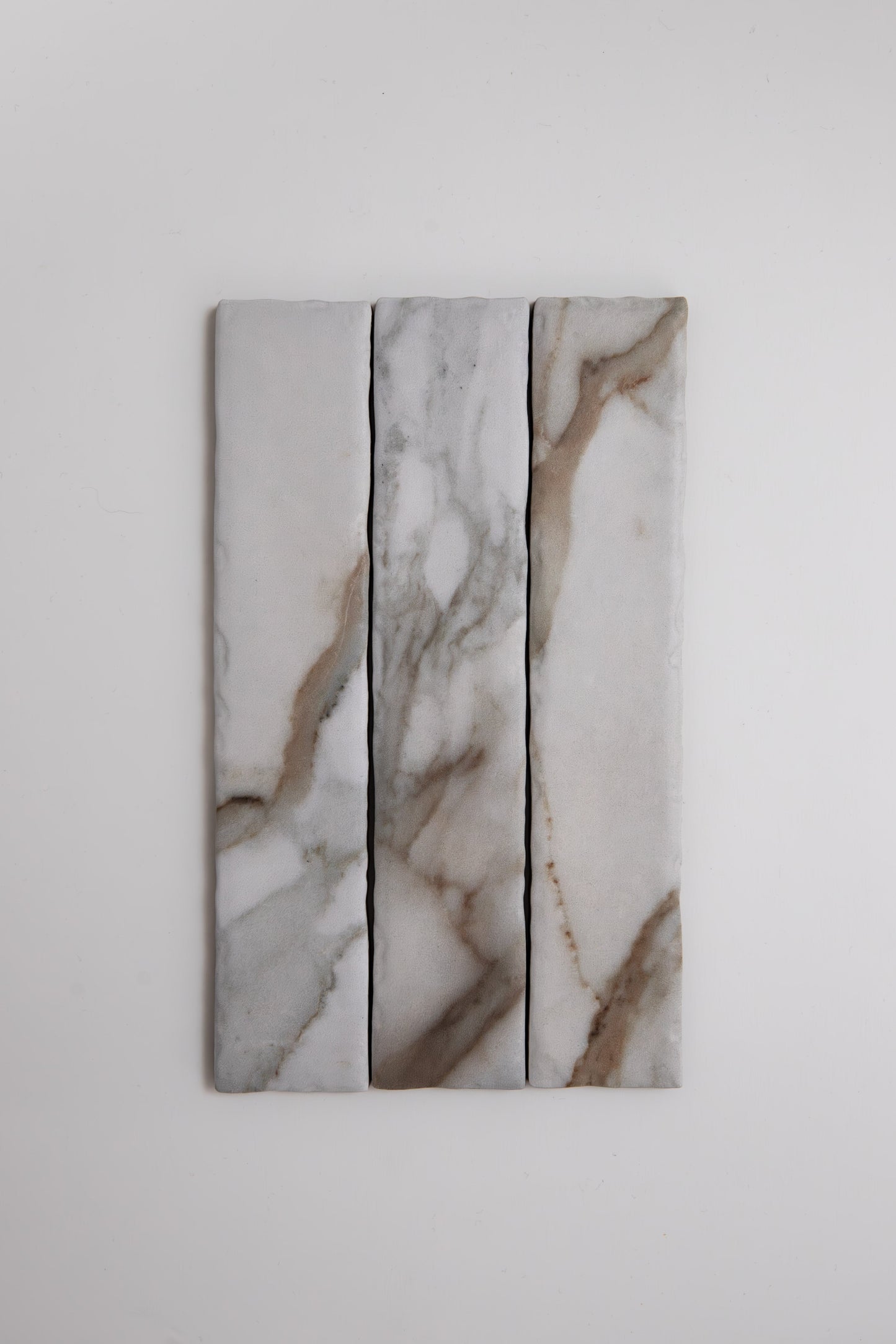 Three Tosca Macchia Vecchia marble samples with gray and brown veining, shown vertically on a white background.