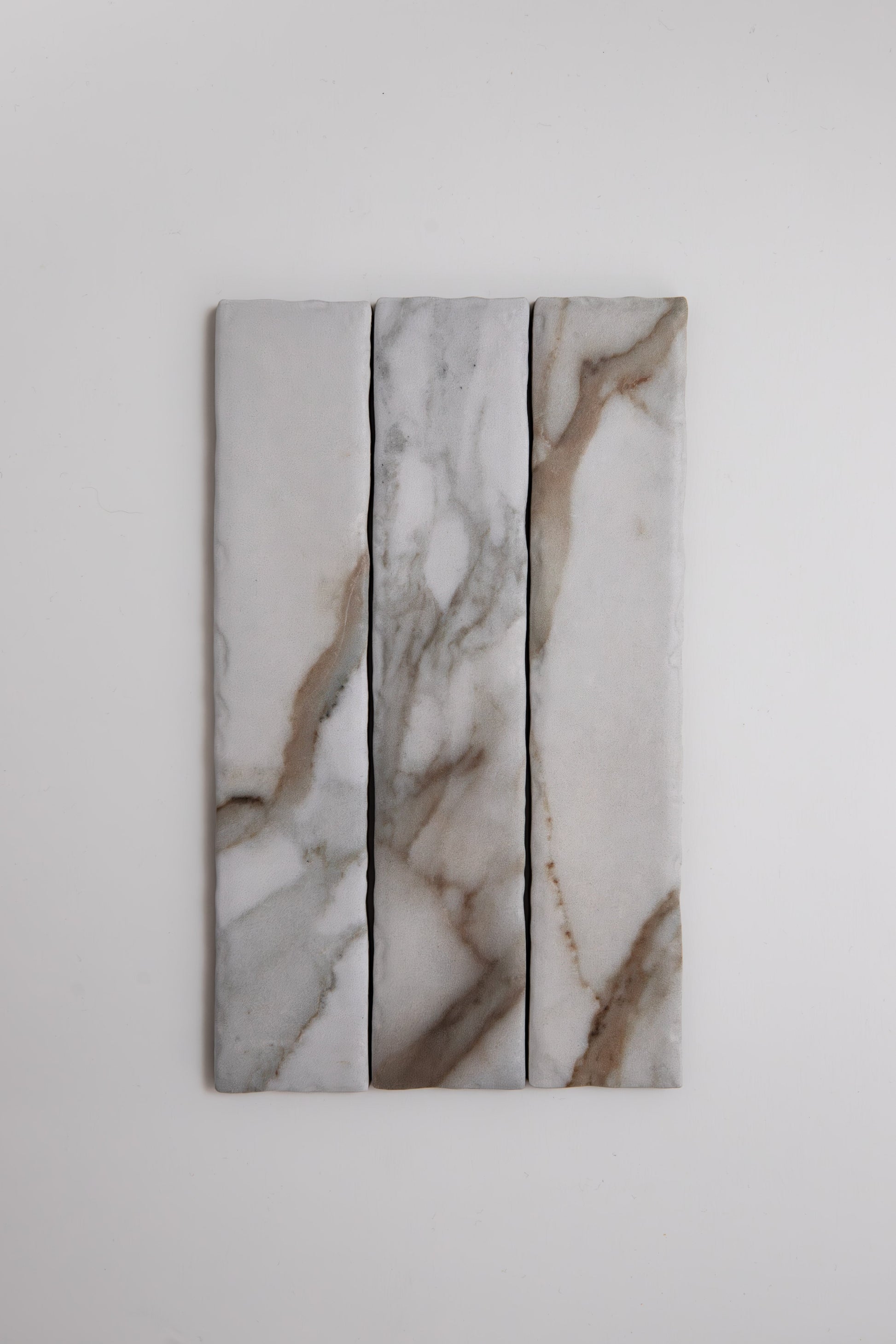 Three Tosca Macchia Vecchia marble samples with gray and brown veining, shown vertically on a white background.
