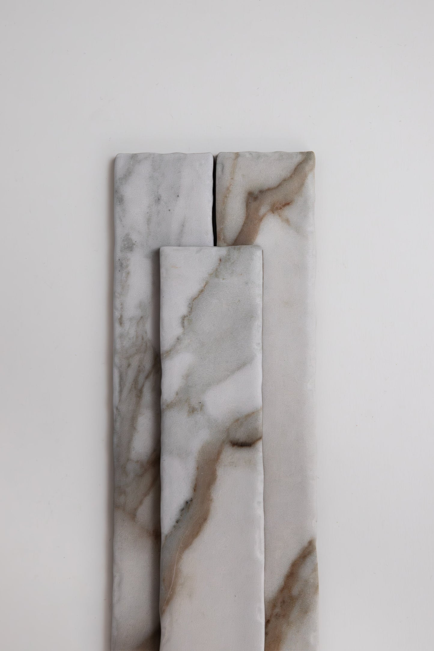 Three Tosca Macchia Vecchia marble tile samples with gray and brown veins arranged vertically on a white background.