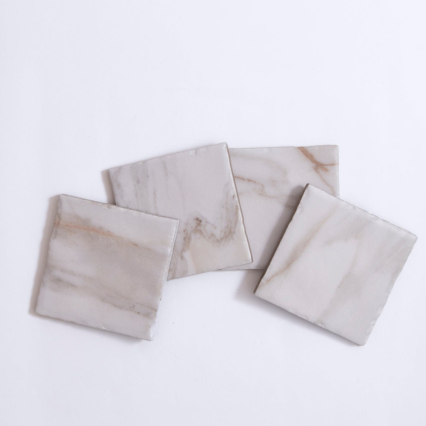 Four Tosca Macchia Vecchia marble sample tiles with light gray and beige veining displayed on a white background.