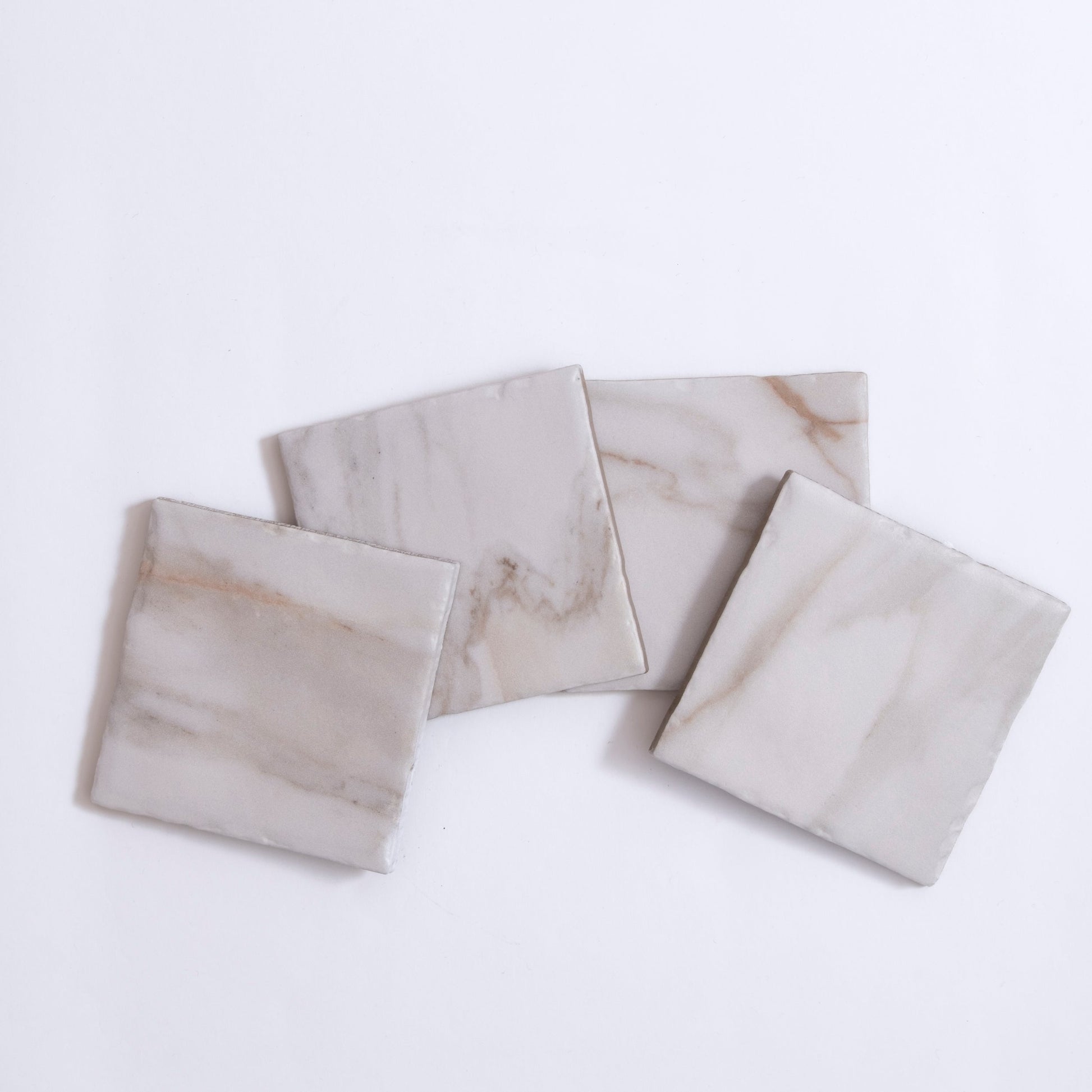 Four Tosca Macchia Vecchia marble sample tiles with light gray and beige veining displayed on a white background.