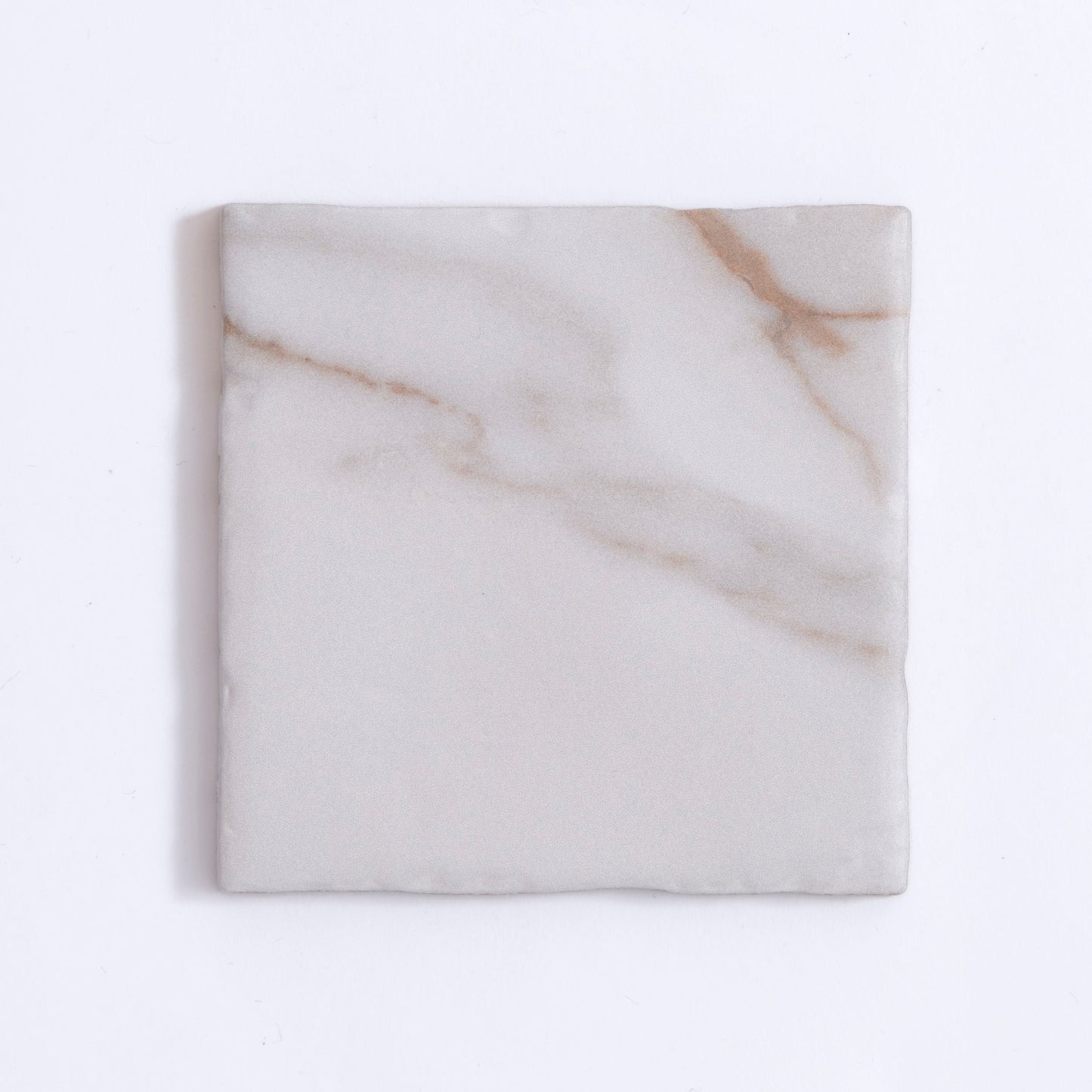 Tosca Macchia Vecchia Sample: a square tile with light gray surface and subtle brownish veins on white.