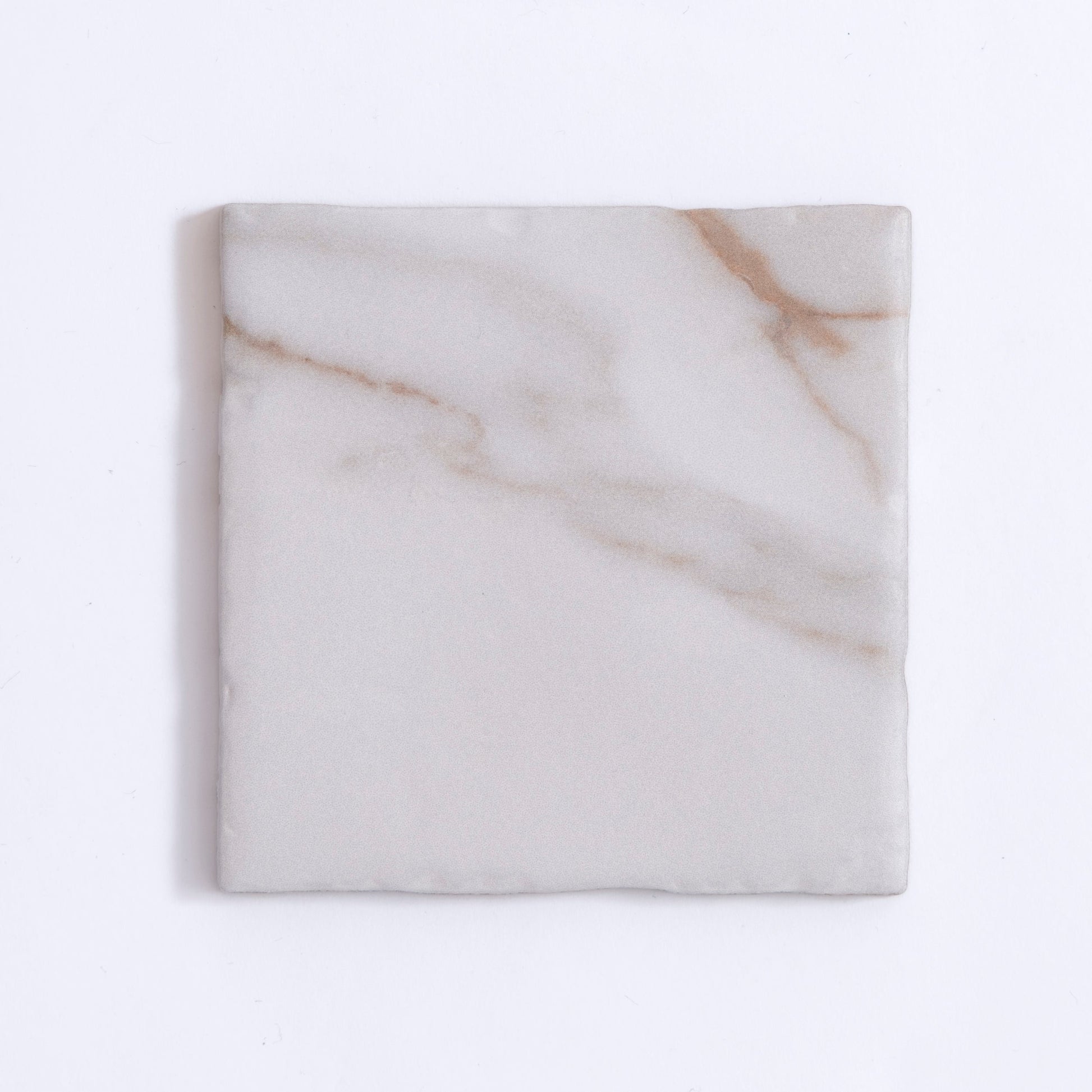 Tosca Macchia Vecchia Sample: a square tile with light gray surface and subtle brownish veins on white.