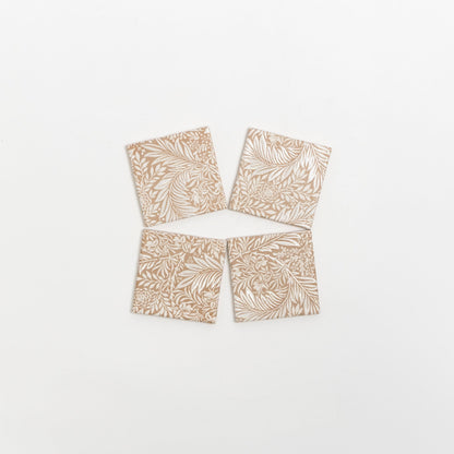 Four Maisie Deco tile samples by Cottage Ivy, beige with white leaf and floral patterns, arranged in a loose diamond shape.