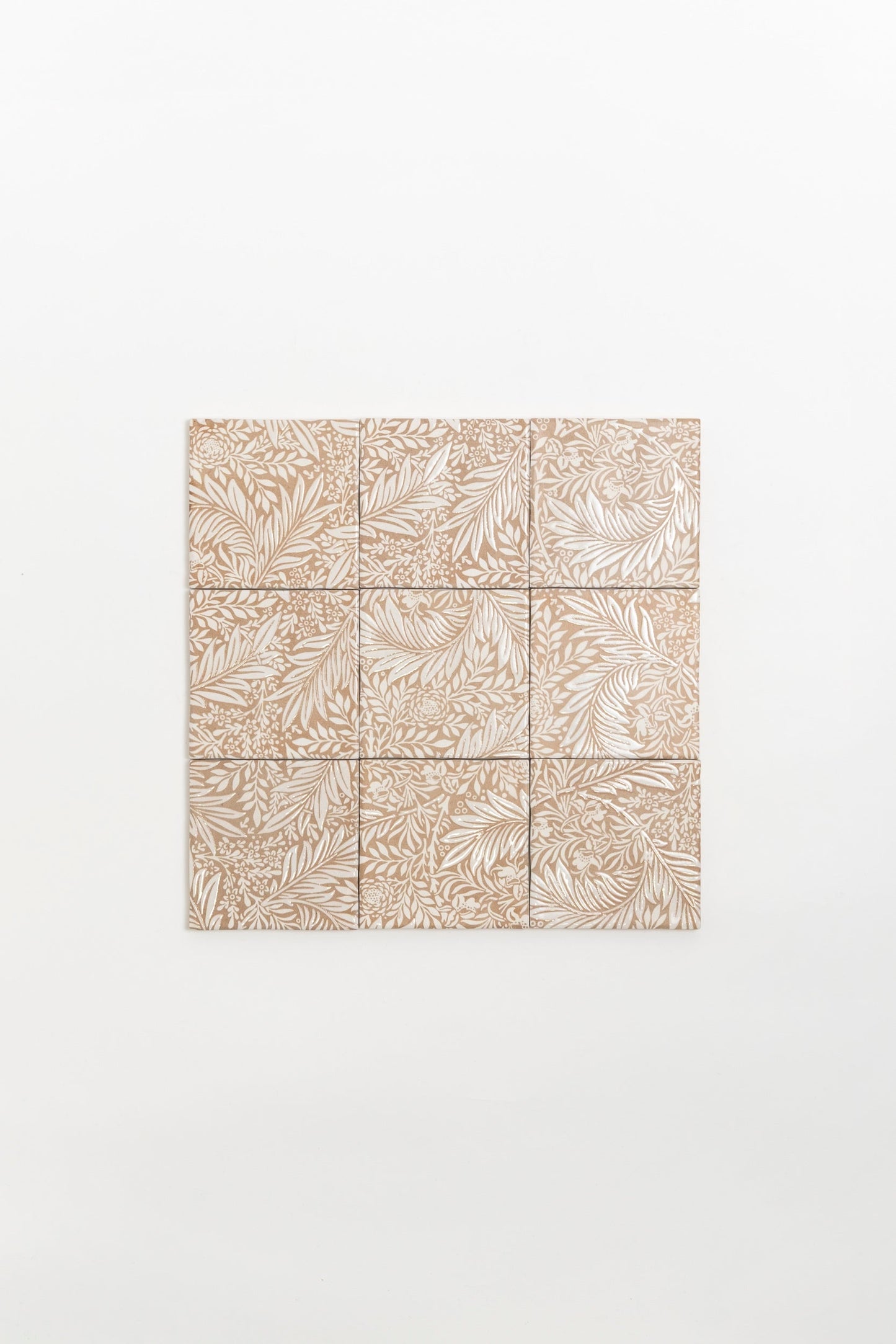 Nine Maisie Deco sample tiles by Cottage Ivy with nature-inspired beige patterns arranged in a square on a white wall.