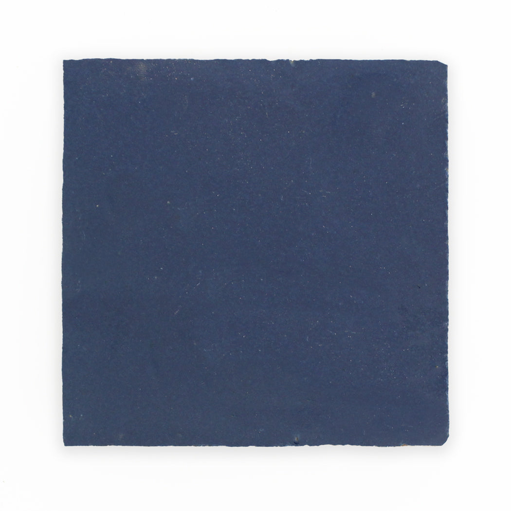 A square Navy Depths tile sample by New York Cement Tile, deep blue with rough texture and uneven edges on white.