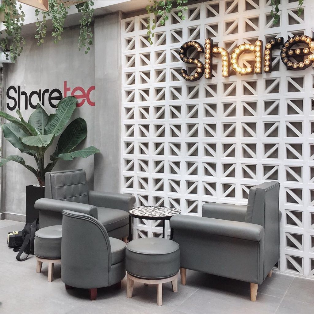 Modern lounge with gray chairs, round stools, and a Kaui concrete screen by New York Cement Tile accenting a white wall.