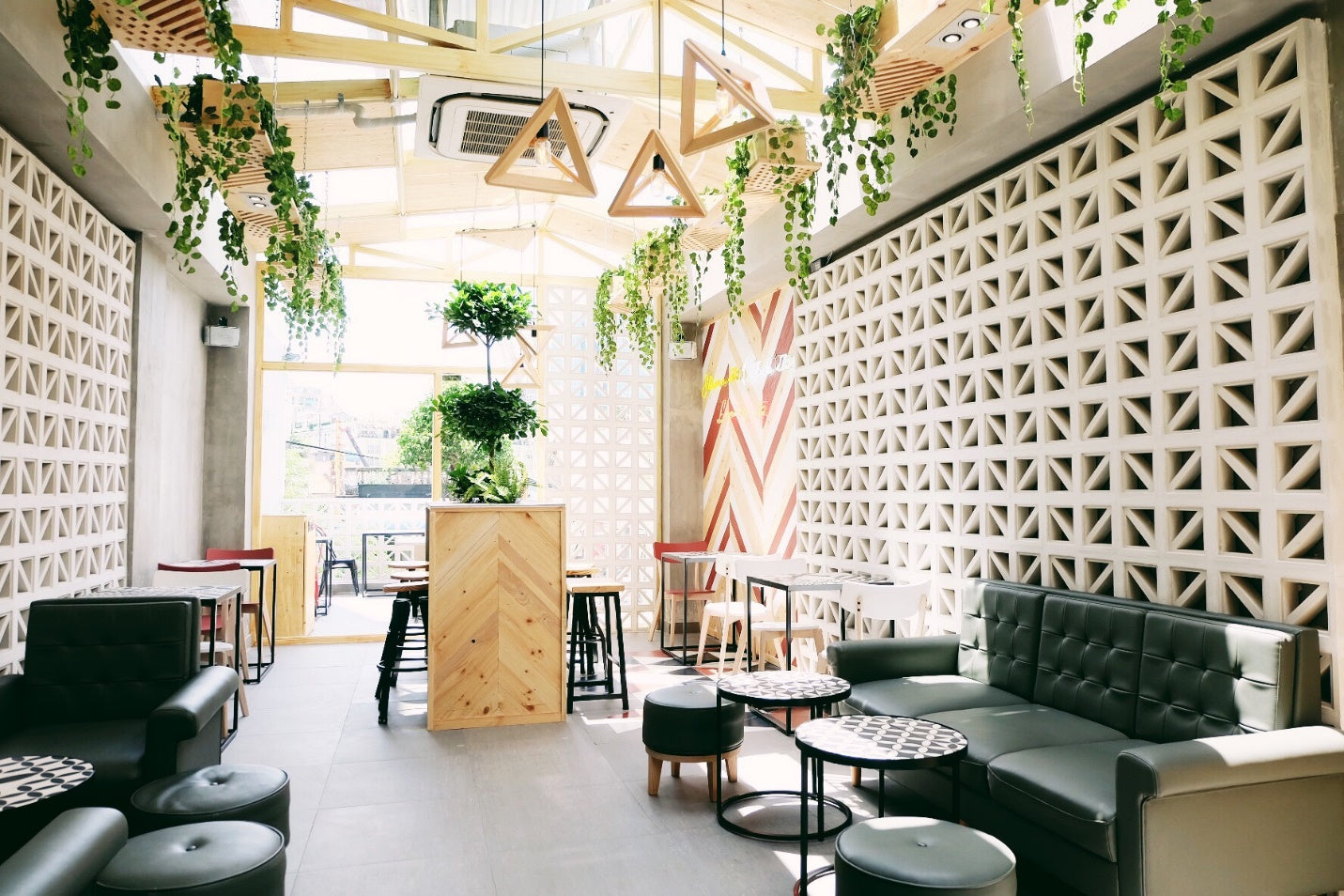 Bright, modern café featuring Kaui tiles by New York Cement Tile, geometric decor, hanging plants, and stylish gray seating.