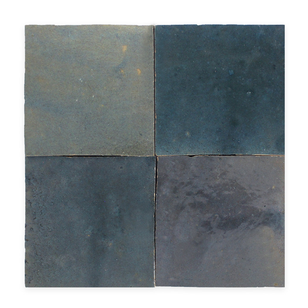 Four square, blue-gray ceramic tiles arranged in a grid with subtle variations in color and texture.
