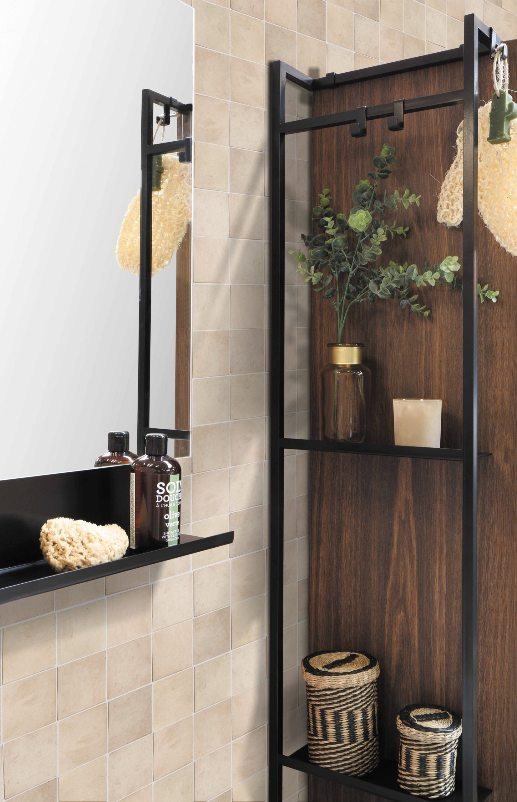 Earthy Clay tiles by New York Cement Tile frame a mirror above a bathroom shelf with plants, jars, and toiletries.