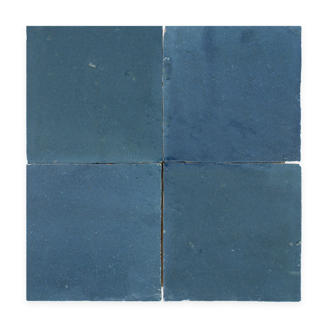 Four square, blue ceramic tiles arranged in a grid on a white background, with slight variations in texture and shade.