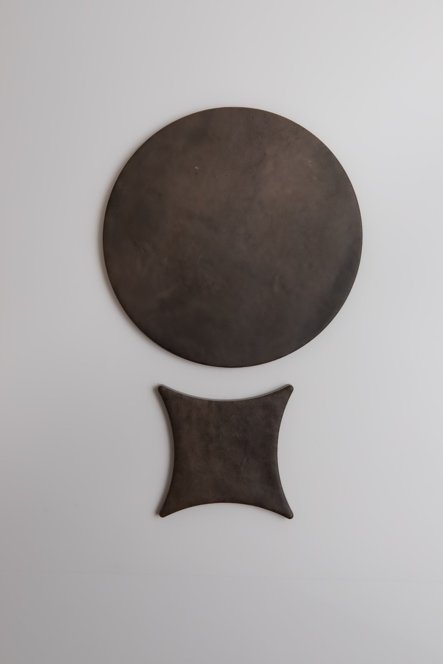 Ocre by New York Cement Tile: a large dark circle above a smaller curved square on a plain white background.