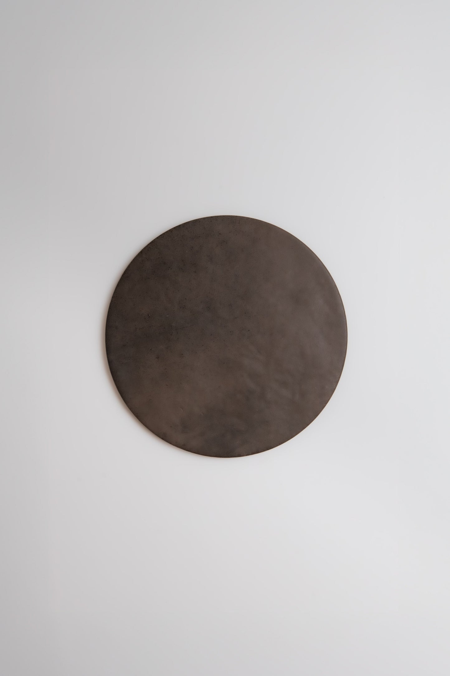 The Finca Ocre, Extra Sample—a large, dark brown circle—hangs on a plain white wall.