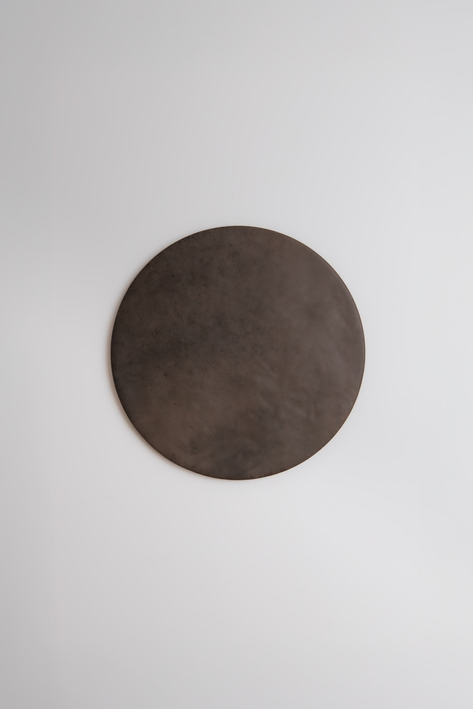 The Finca Ocre, Extra Sample—a large, dark brown circle—hangs on a plain white wall.