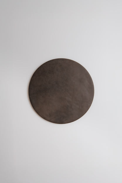 The Finca Ocre, Extra Sample—a large, dark brown circle—hangs on a plain white wall.