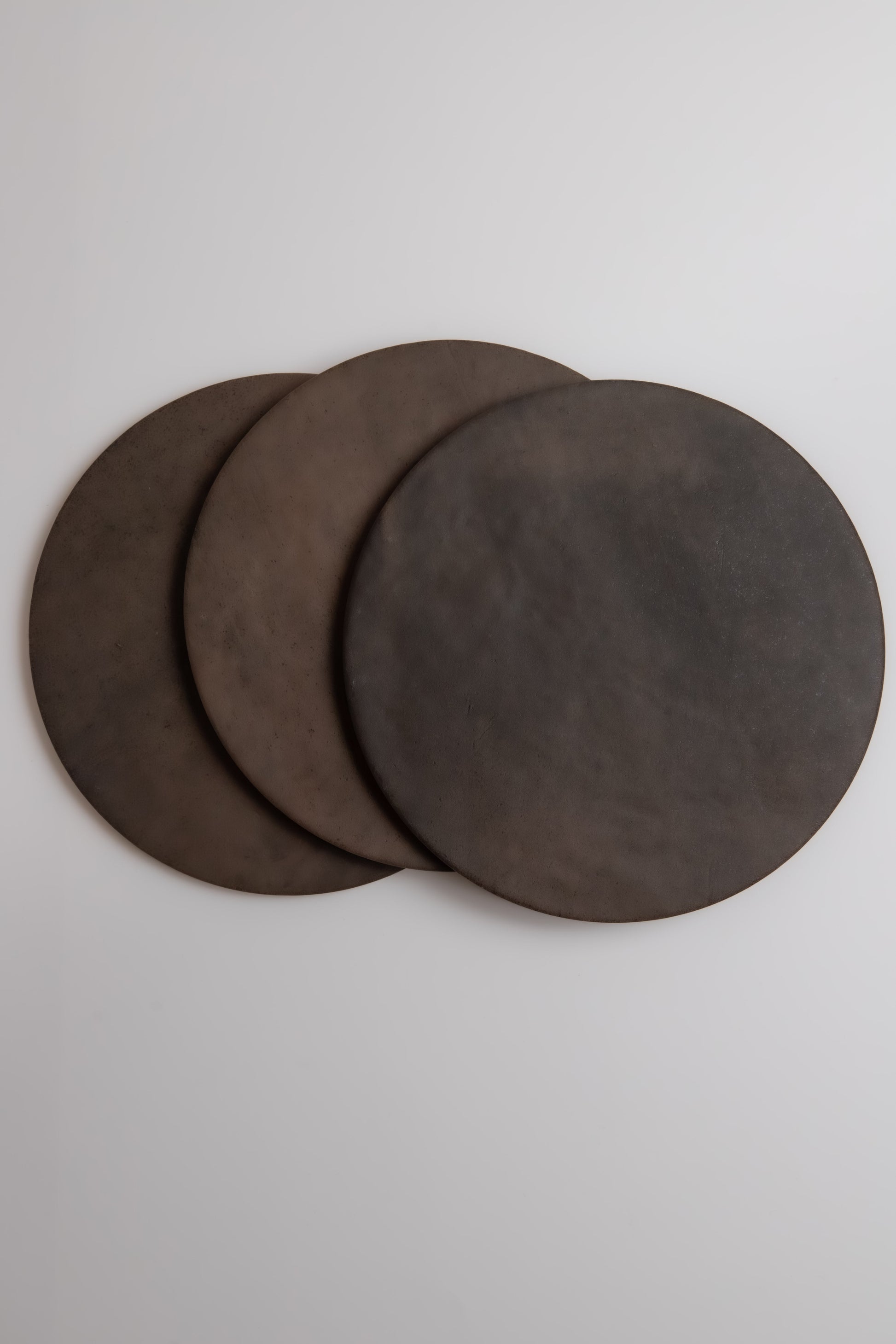 Three Finca Ocre, Extra Sample pizza stones overlap on a light surface.