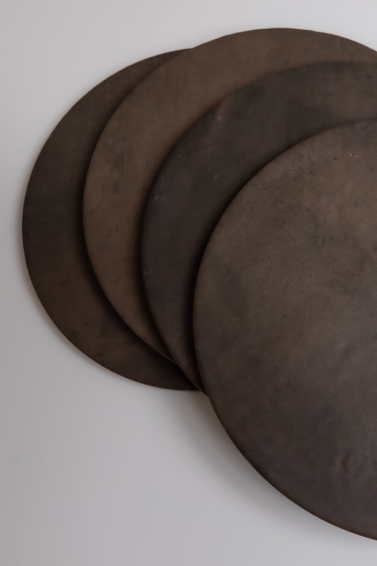 Four round, dark Ocre, Extra Sample plates by Finca overlap on a white surface.