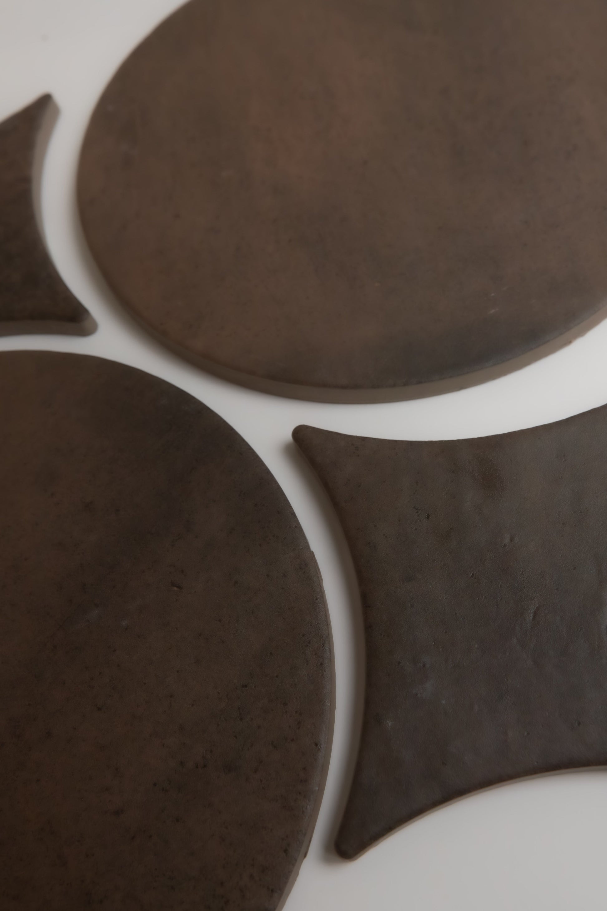 Four Ocre, Extra Sample clay shapes by Finca—two circles and two bow ties—displayed on a white surface.