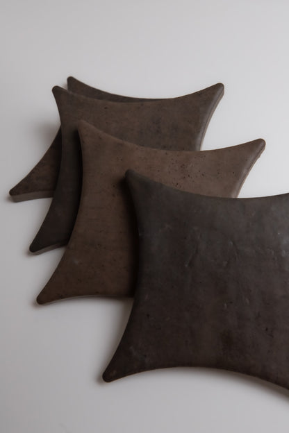 Four Ocre, Extra Sample square plates by Finca are arranged diagonally on a white surface.