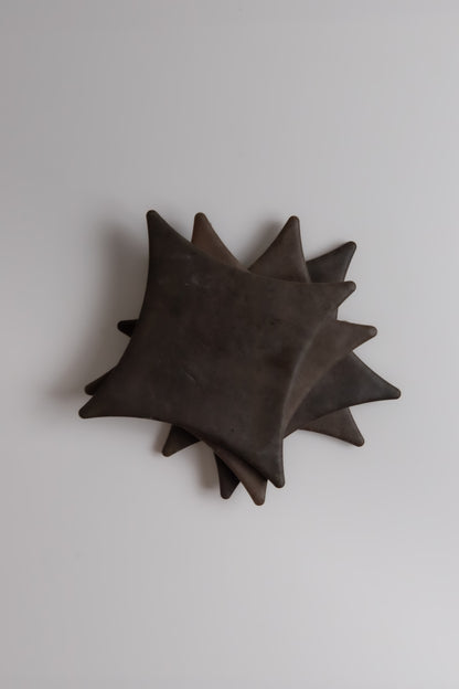 Four square, dark brown Finca Ocre Extra Sample cookies stacked on a light gray background.