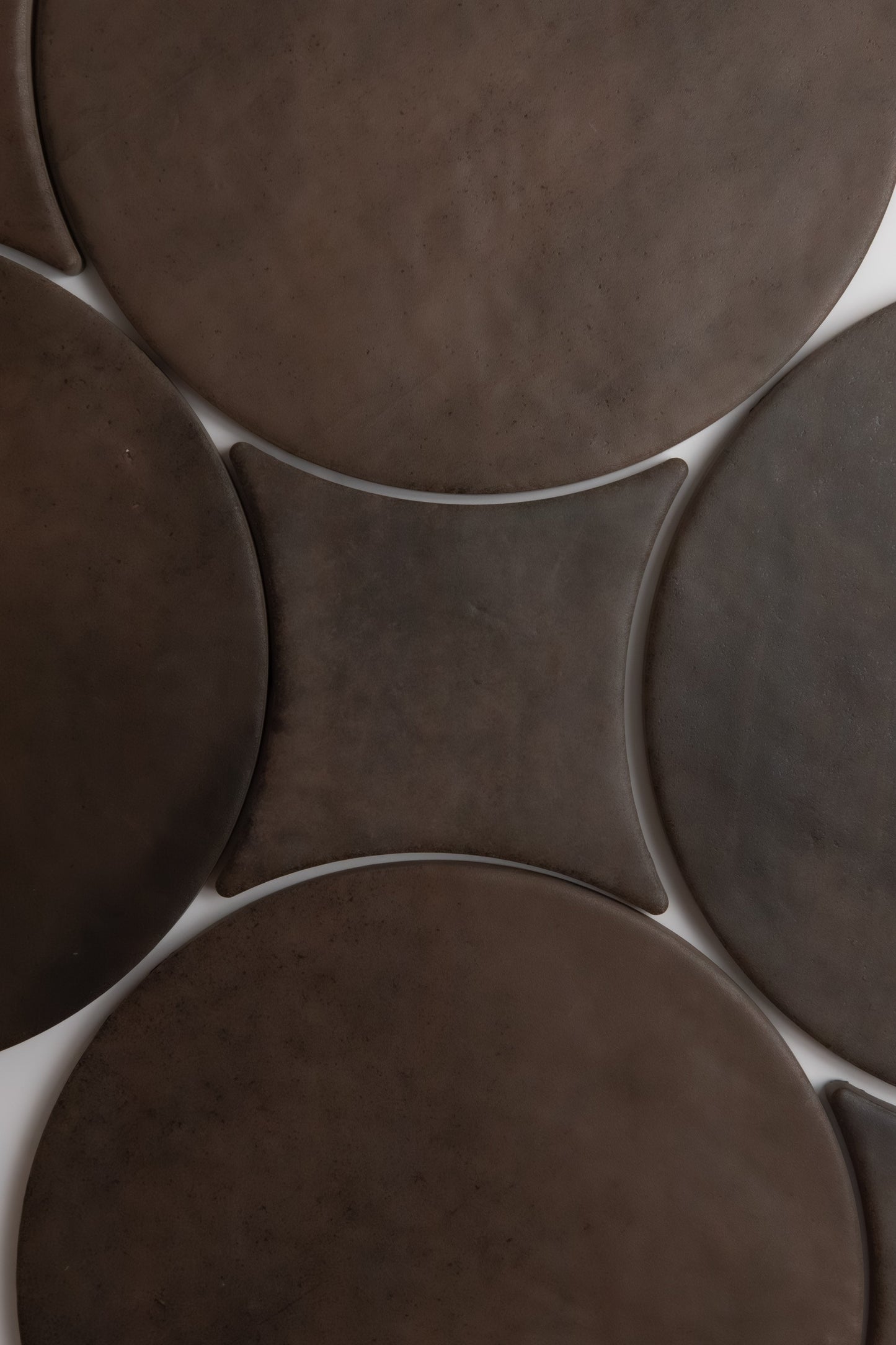 Close-up of Finca's Ocre, Extra Sample mats—several round, dark brown pieces with a diamond-shaped one in the center.