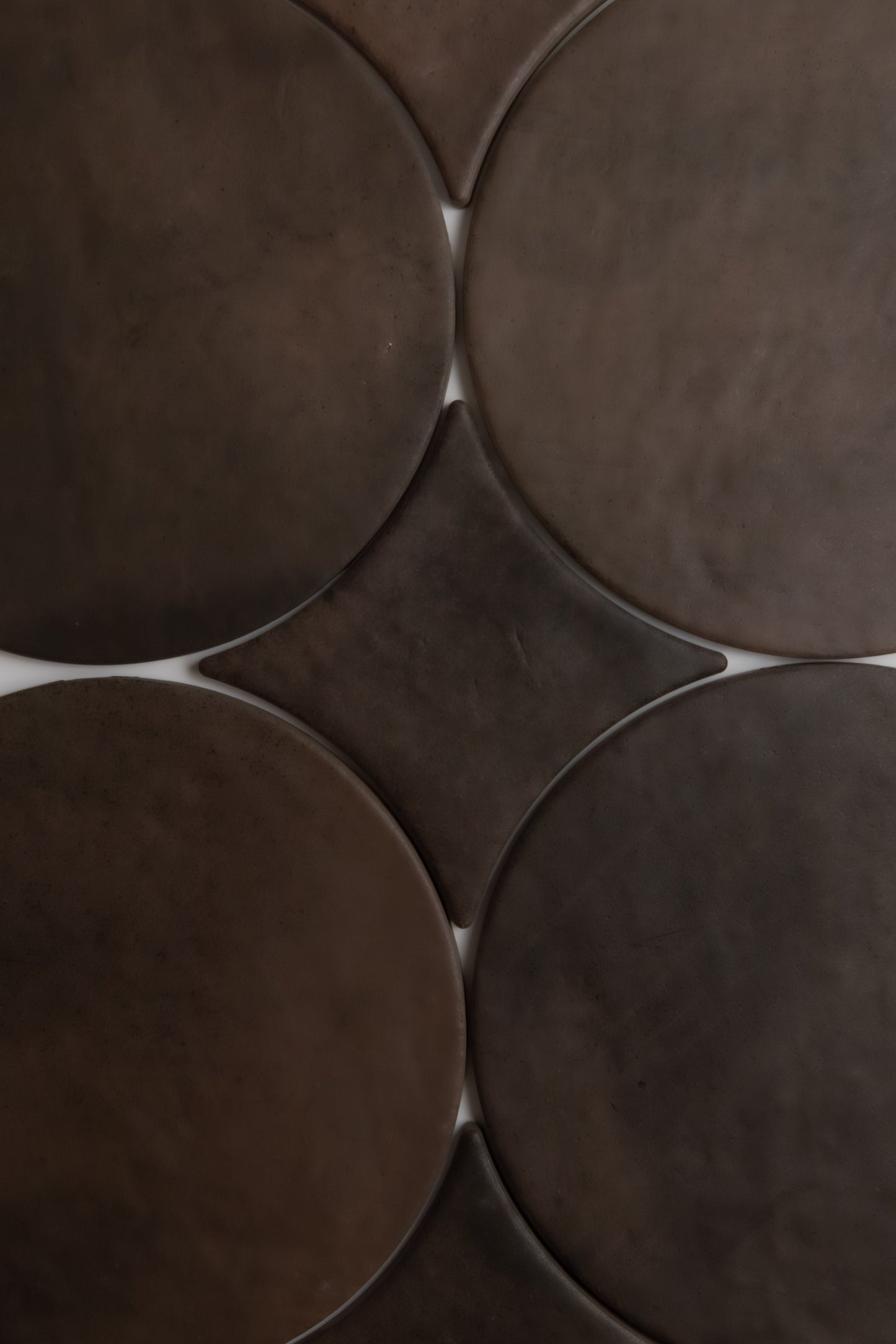 Close-up of Finca’s Ocre, Extra Sample: overlapping dark brown tiles form a geometric, abstract pattern.