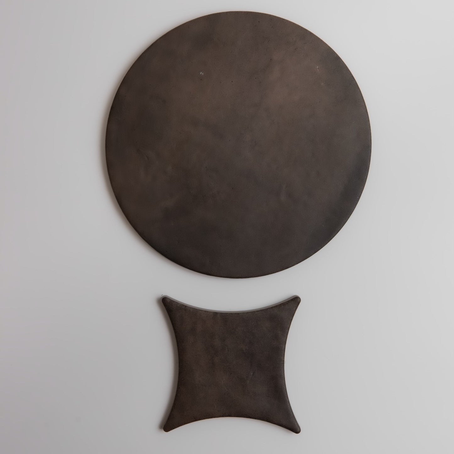 A large, round dark disk sits above a smaller four-cornered shape in the Finca Ocre, Extra Sample.