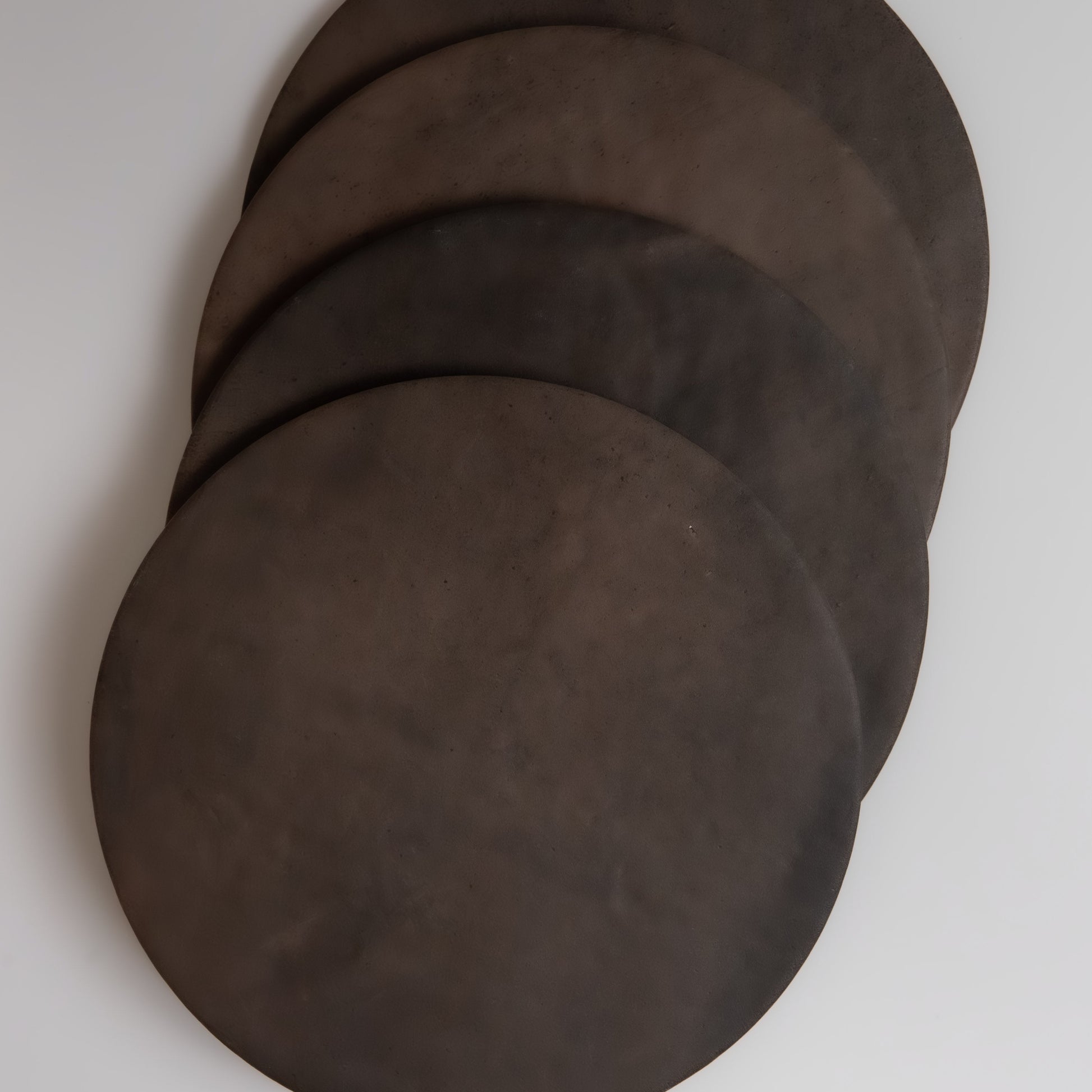 Five round, dark brown Finca Ocre, Extra Sample tortillas overlap each other on a white surface.