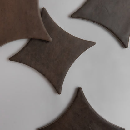 Four Ocre, Extra Sample tiles by Finca, dark brown and diamond-shaped, are arranged on a light gray background.