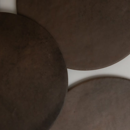 Three overlapping, round, dark brown Finca Ocre Extra Sample surfaces on white, resembling ceramic or stone plates.