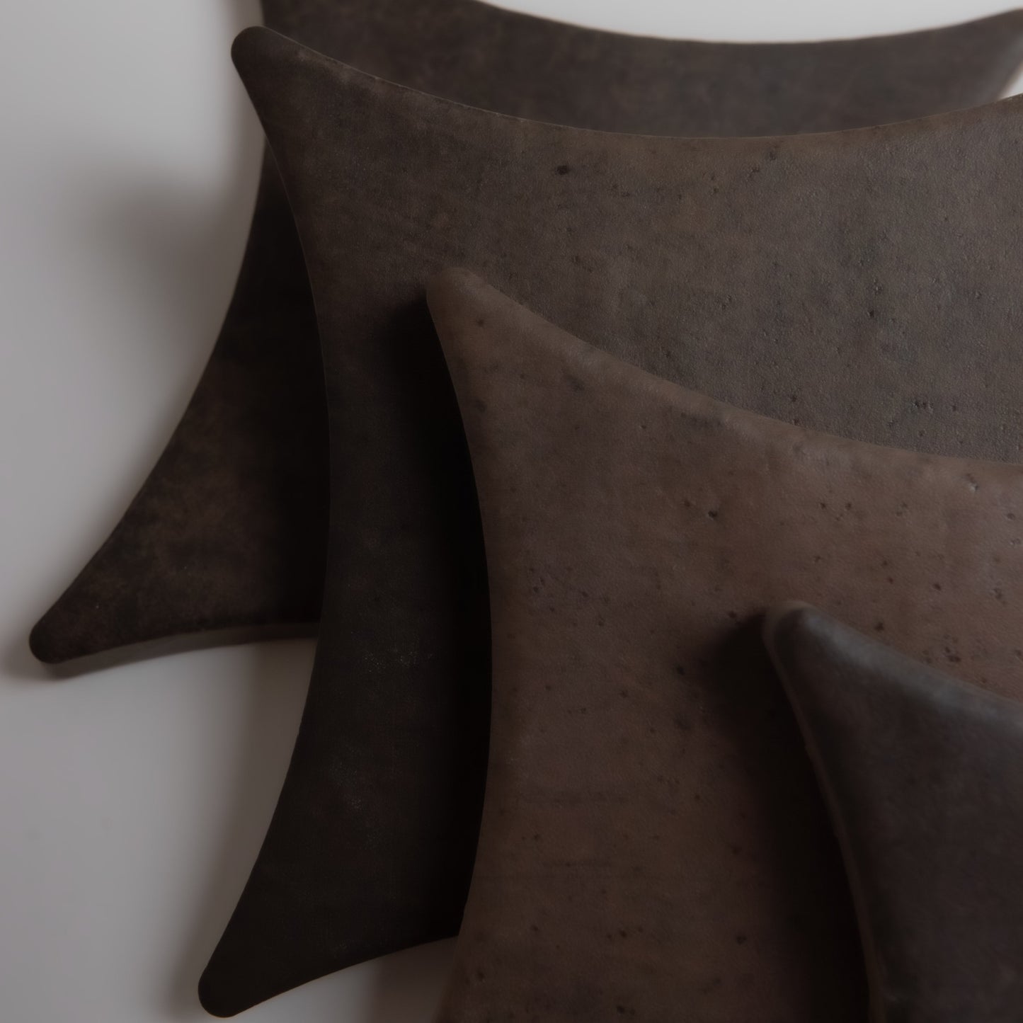 Four curved, dark brown Ocre, Extra Sample tiles by Finca, fanned on a light background.