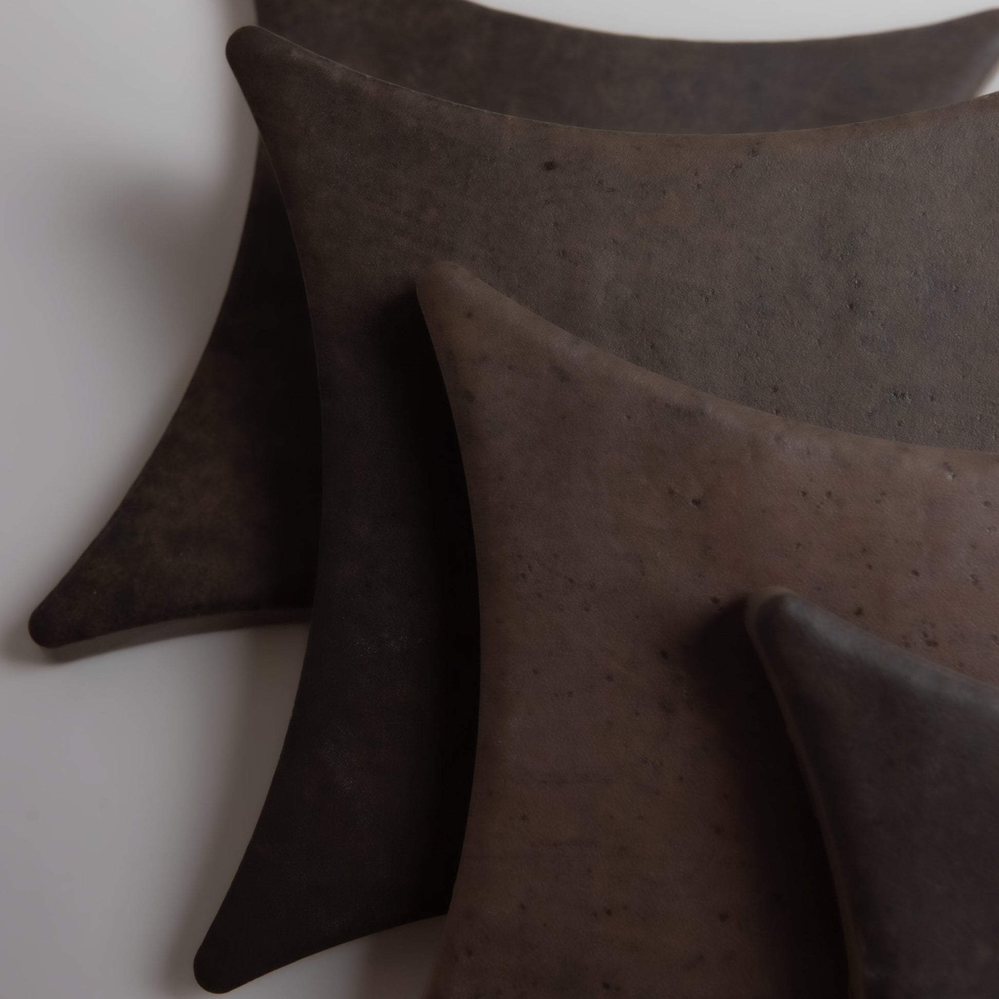 Four curved, dark brown Ocre, Extra Sample tiles by Finca, fanned on a light background.