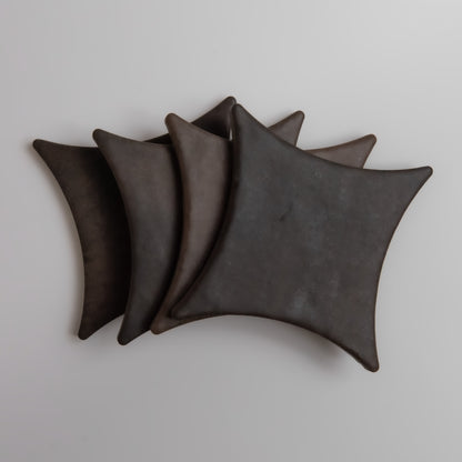 Four overlapping, dark, curved square shapes from Finca's Ocre, Extra Sample on a light background.