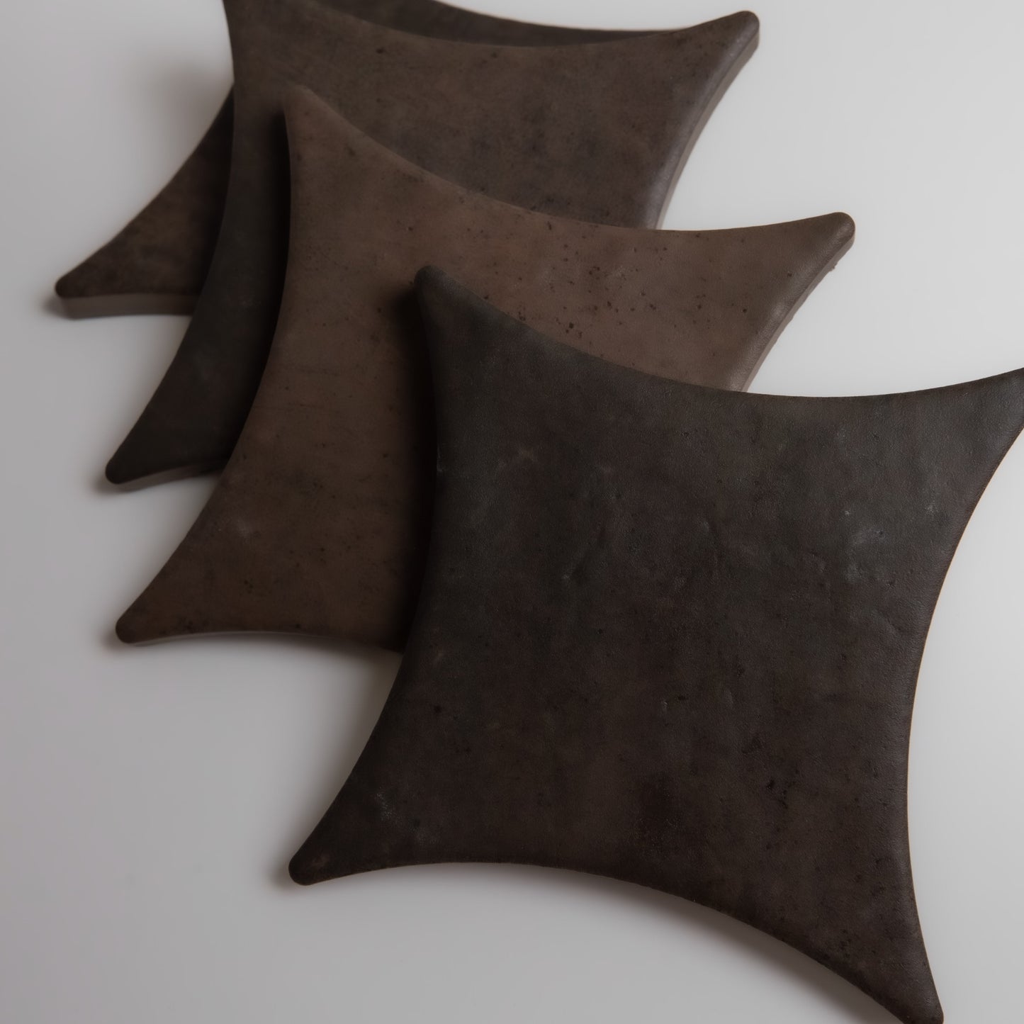 Four Finca Ocre Extra Sample tiles with curved edges are arranged diagonally on a white surface.