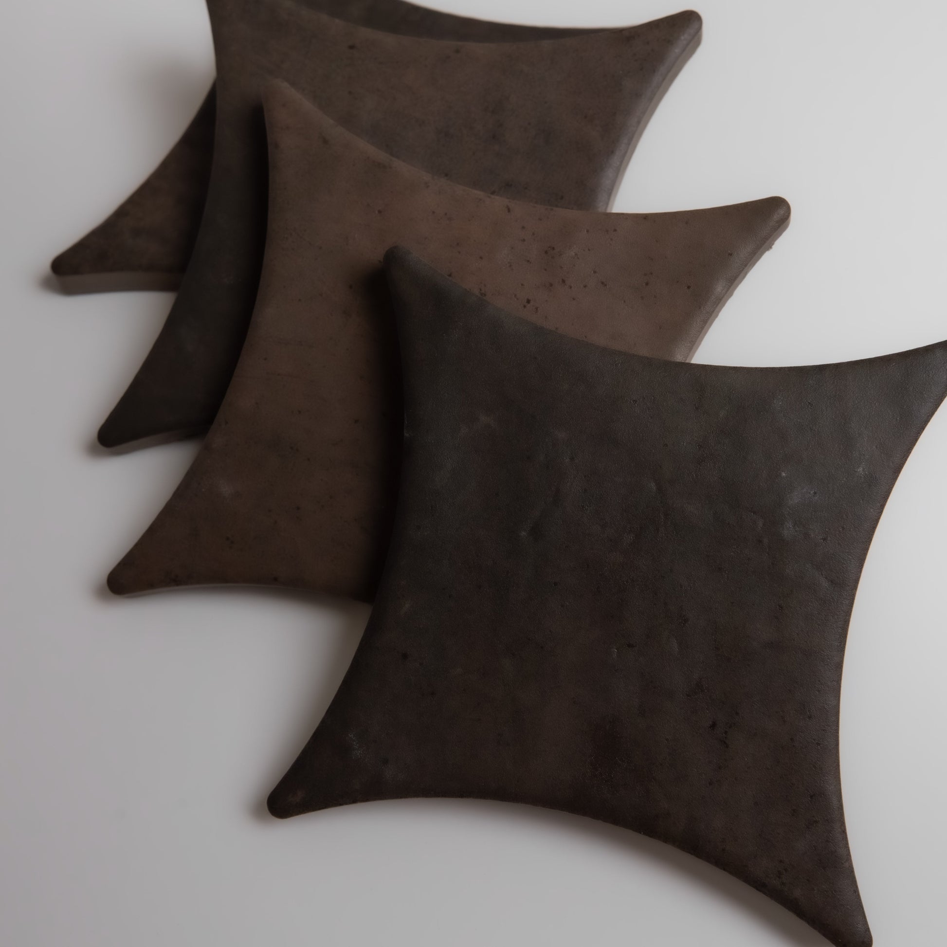 Four Finca Ocre Extra Sample tiles with curved edges are arranged diagonally on a white surface.