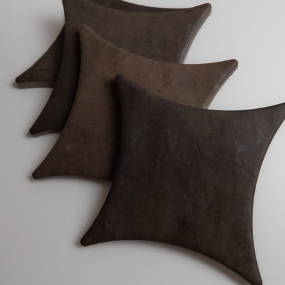 Four Finca Ocre Extra Sample tiles with curved edges are arranged diagonally on a white surface.