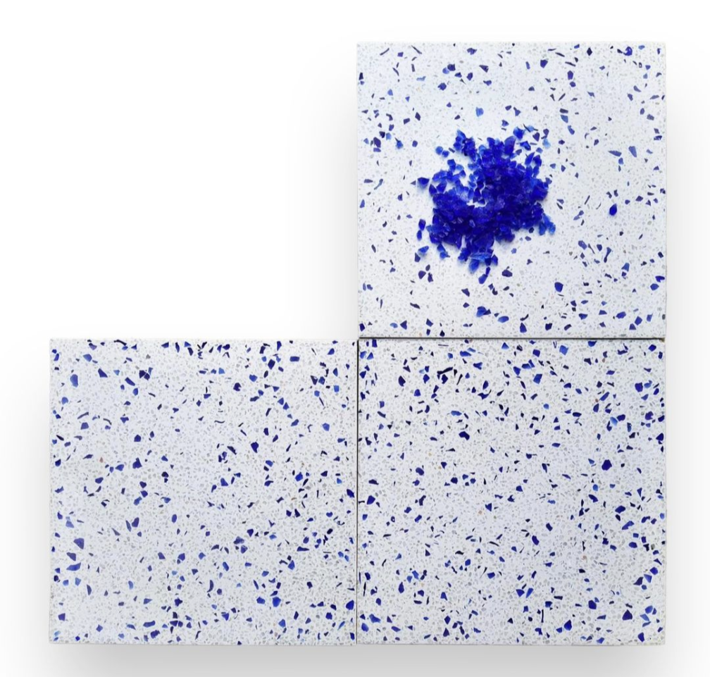 Three white tiles with blue speckles; the top-right tile has a concentrated blue stain or splash near its center.