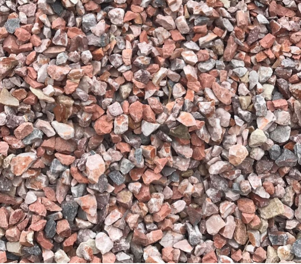 A close-up view of small, irregularly shaped rocks in shades of pink, gray, and brown, scattered closely together.