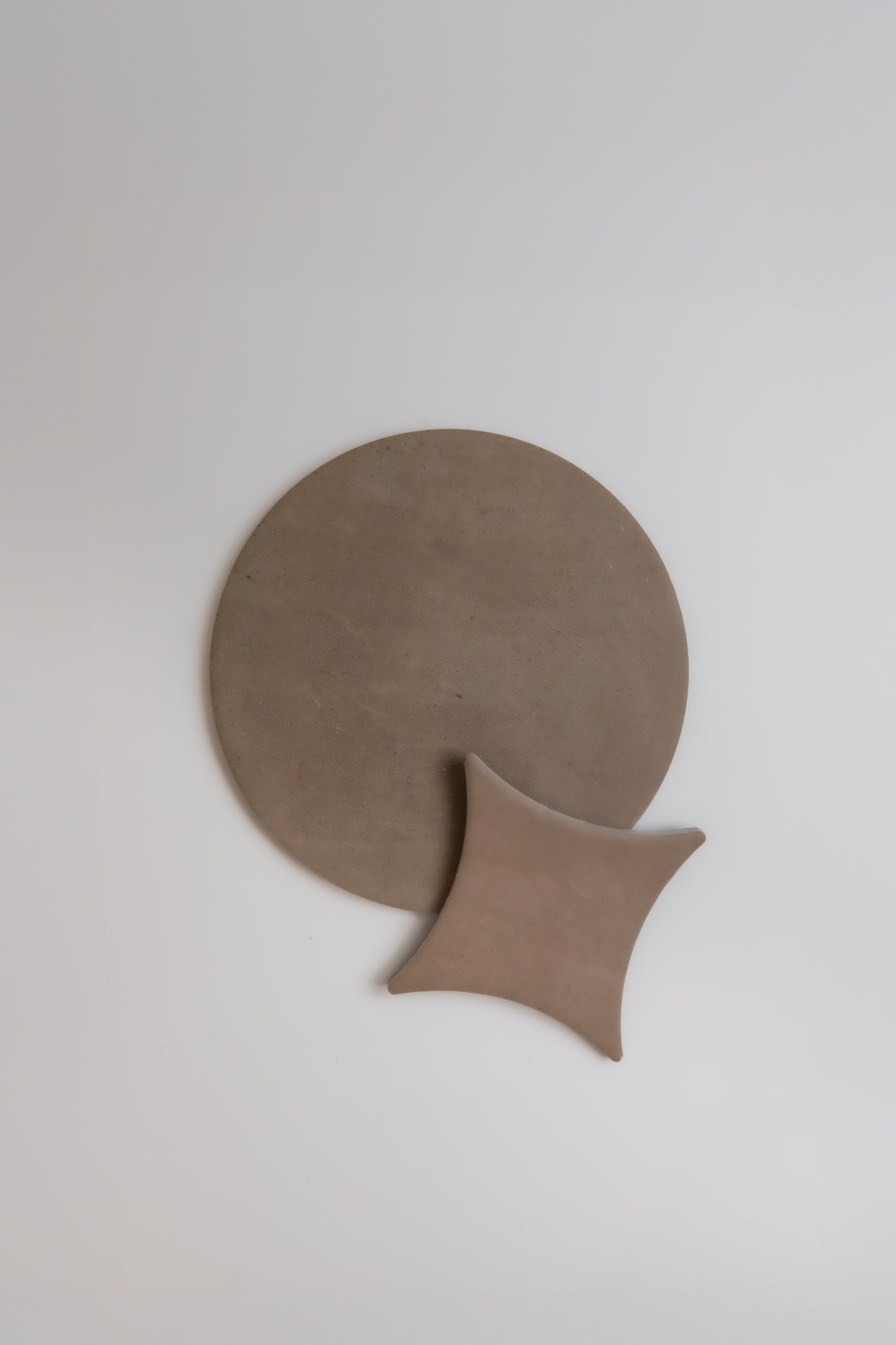 Pampas by New York Cement Tile: two minimalist brown shapes—a large circle and a small curve—on a plain white background.